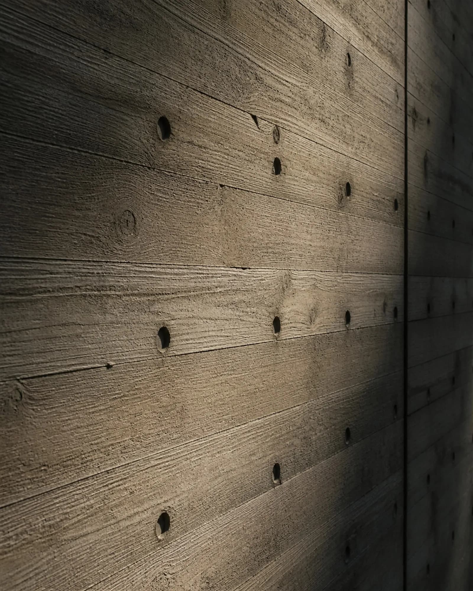 Board-formed concrete filling the frame, showing timber board grain and tie-hole pattern