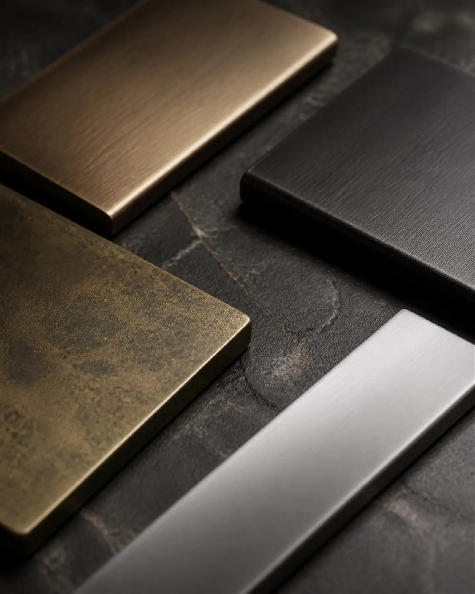 Brushed bronze, blackened steel, patinated brass and stainless samples on dark stone