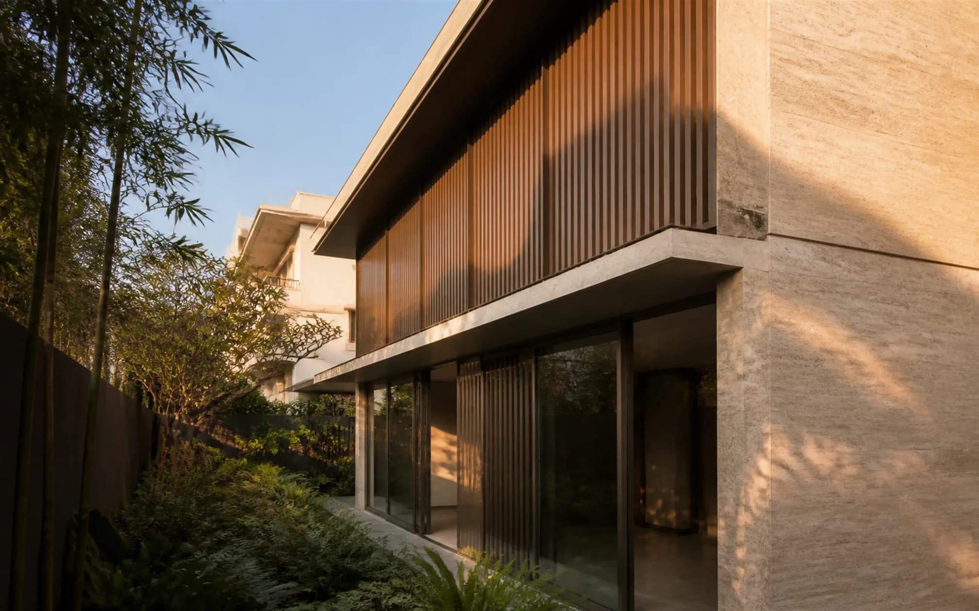 East elevation with a full-height teak louvred screen and slim bronze-framed glazing onto a planted side strip