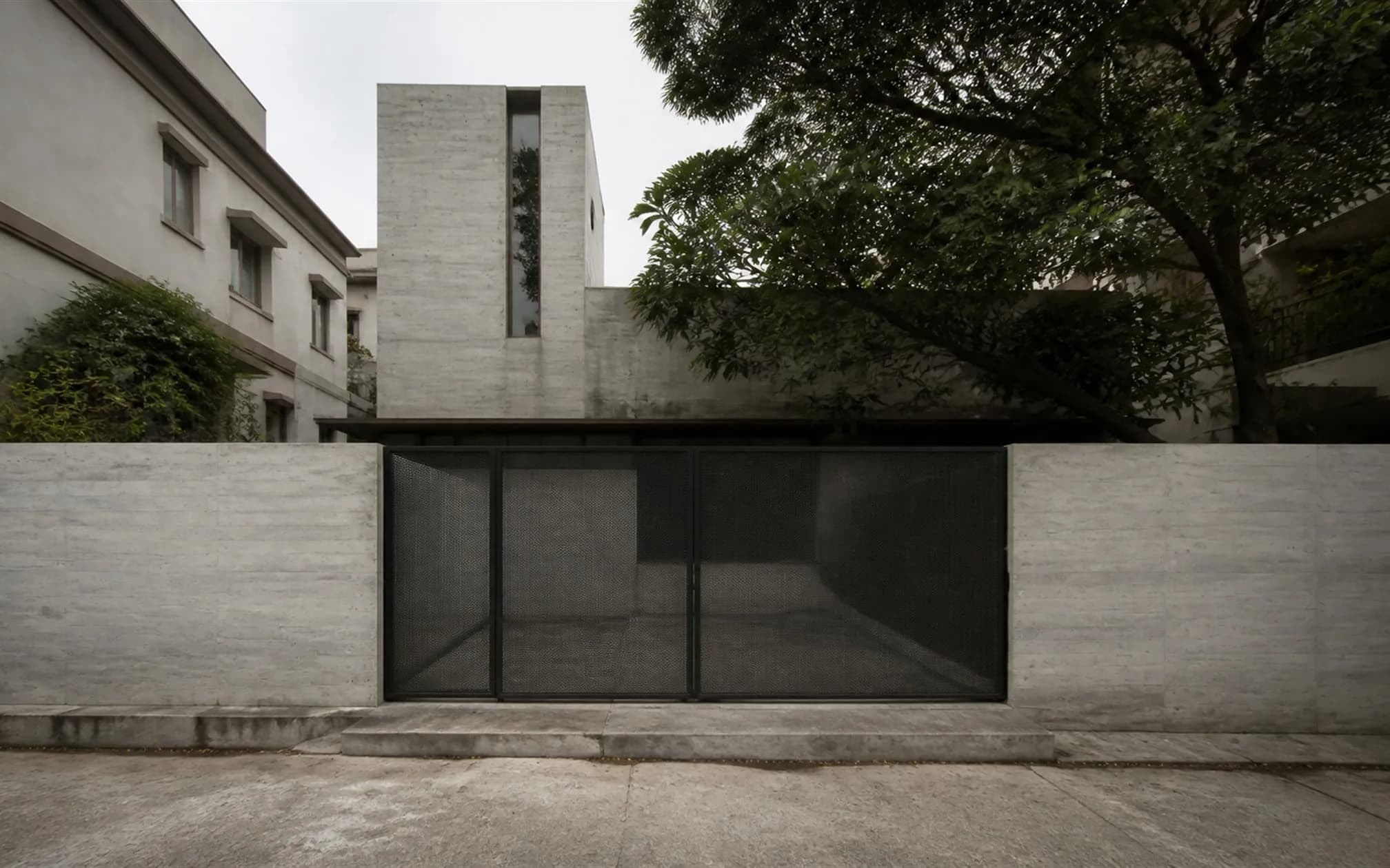 Rear elevation in smooth grey concrete with a screened service court and an expressed stair tower