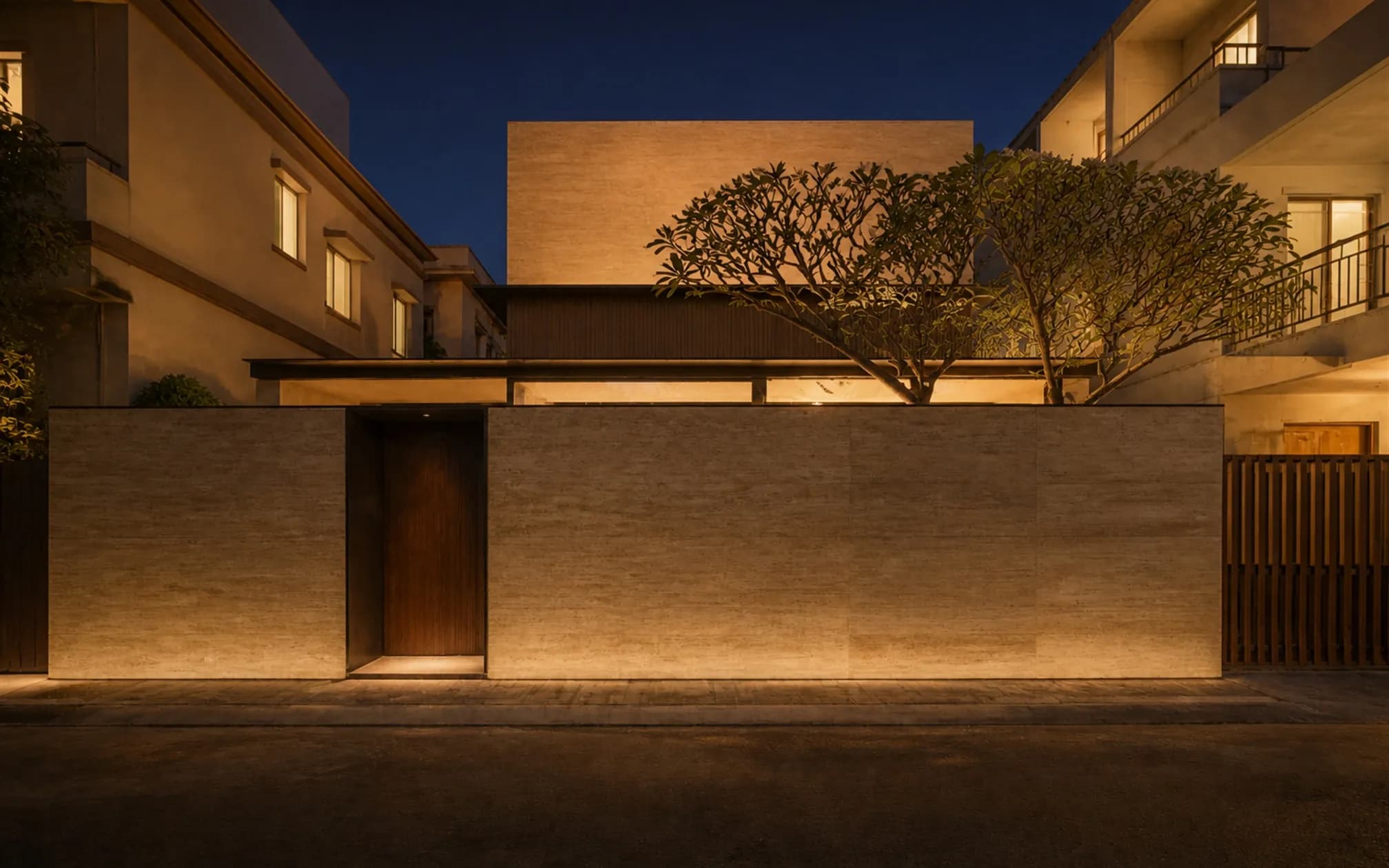 The courtyard at blue hour, warm light glowing from every surrounding room and reflecting in the still pool
