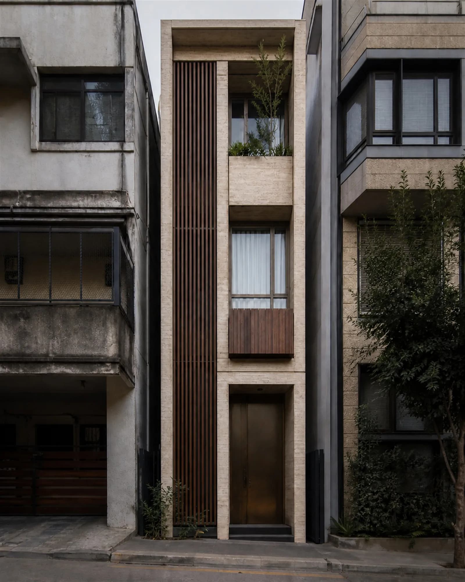 Front elevation — a tall slim three-storey composition of travertine planes and a full-height teak louvre screen