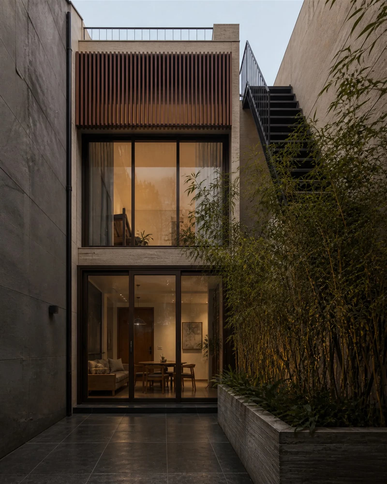 Rear elevation opening onto a small private court with bamboo in a board-formed concrete planter