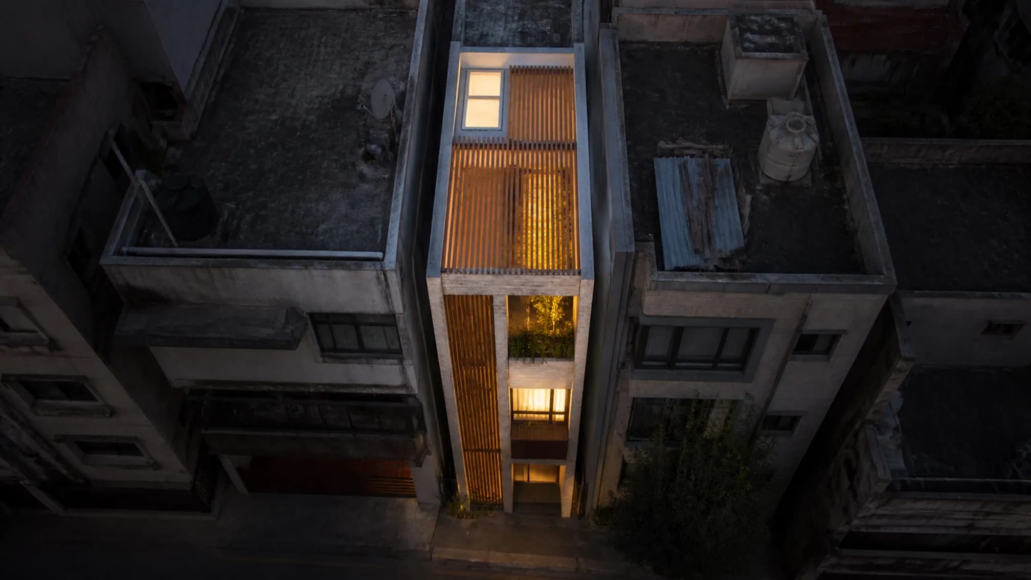 Aerial view showing the light slot cutting through the plan, a planted roof terrace and skylights over the stair