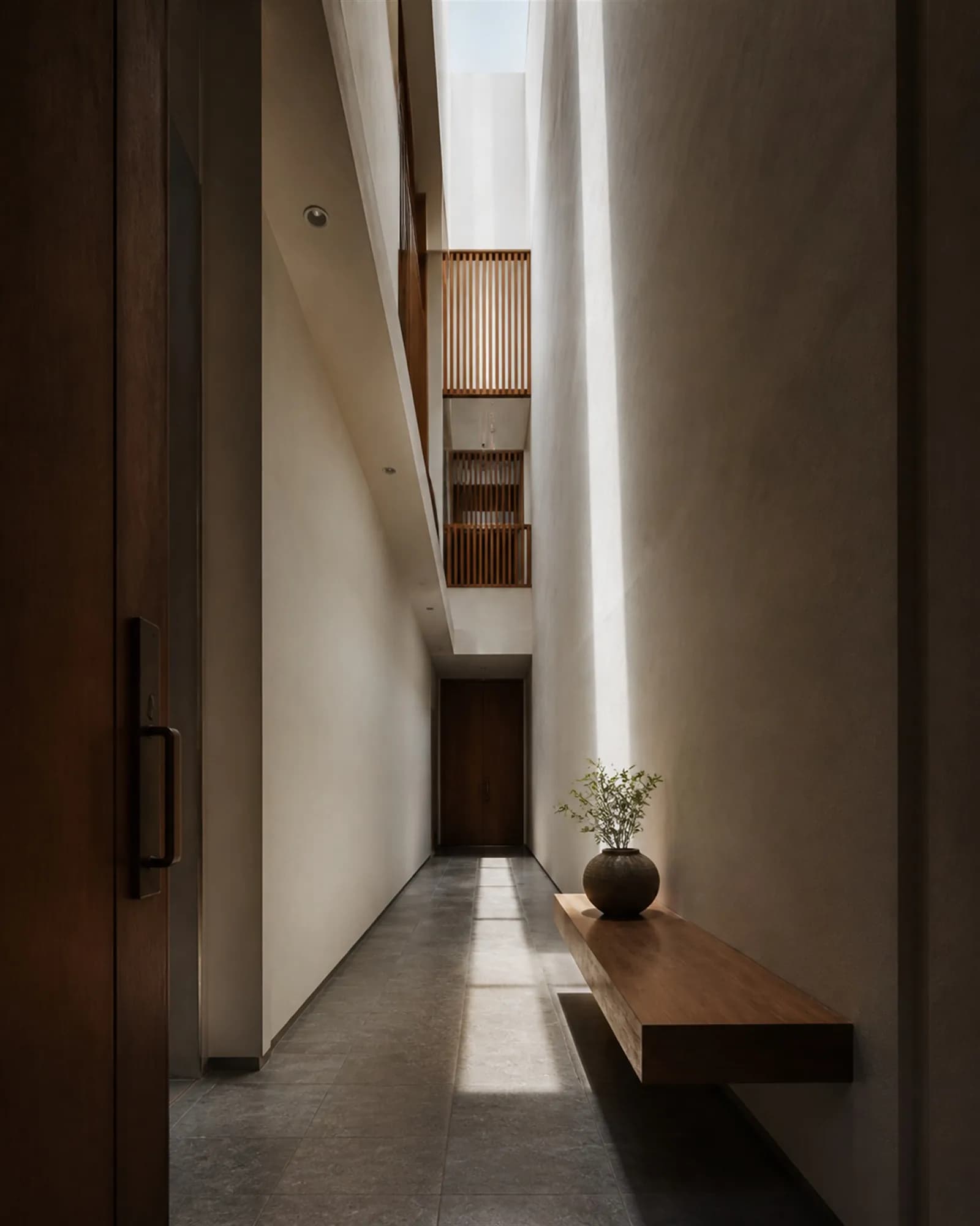 Entrance hall looking down its full length with daylight washing down from a slot three floors above