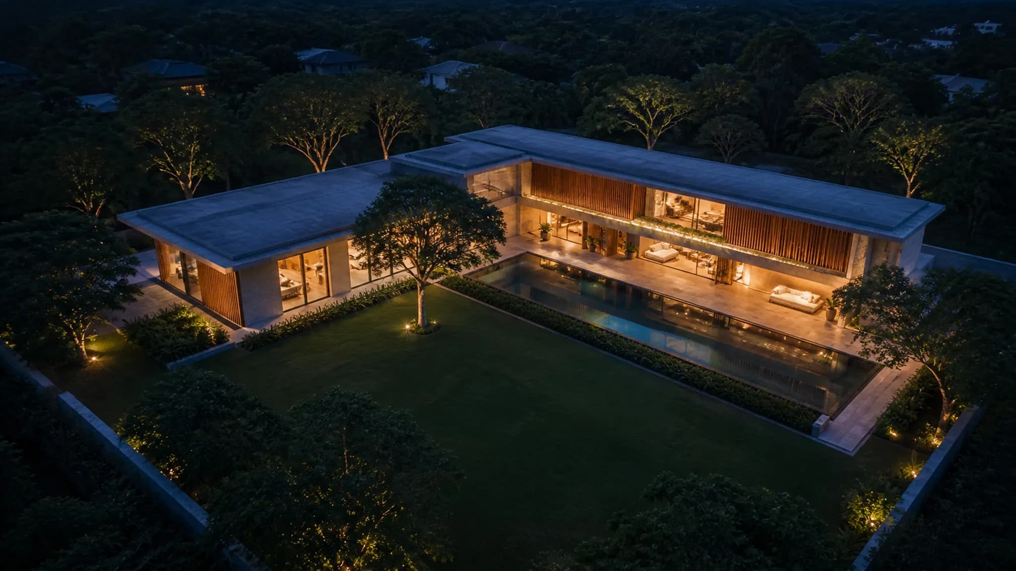 Aerial view of the L-shaped plan embracing a lawn and a long reflecting pool, mature rain trees at the boundary