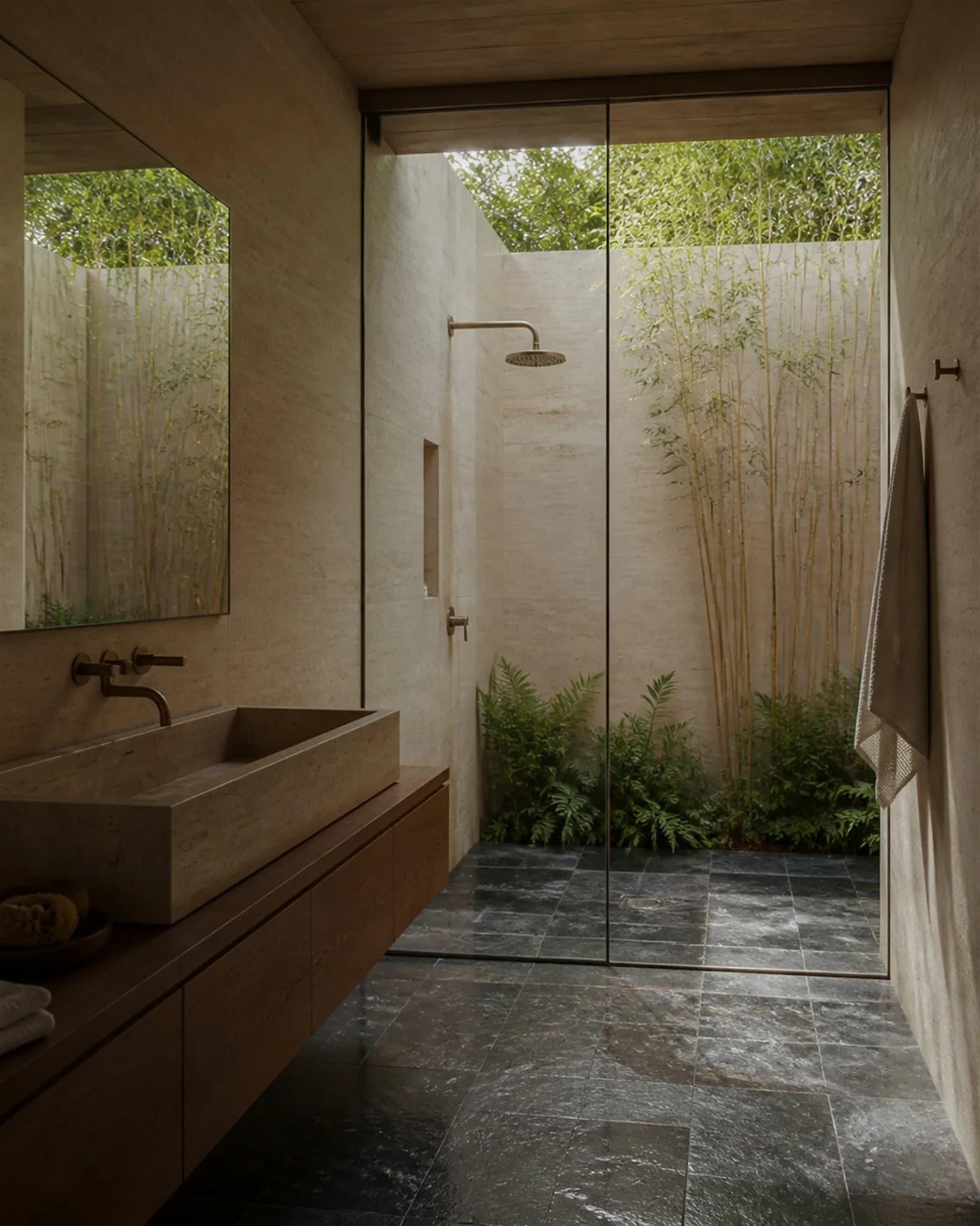 Bathroom with a walled outdoor shower court beyond frameless glass, open to the sky