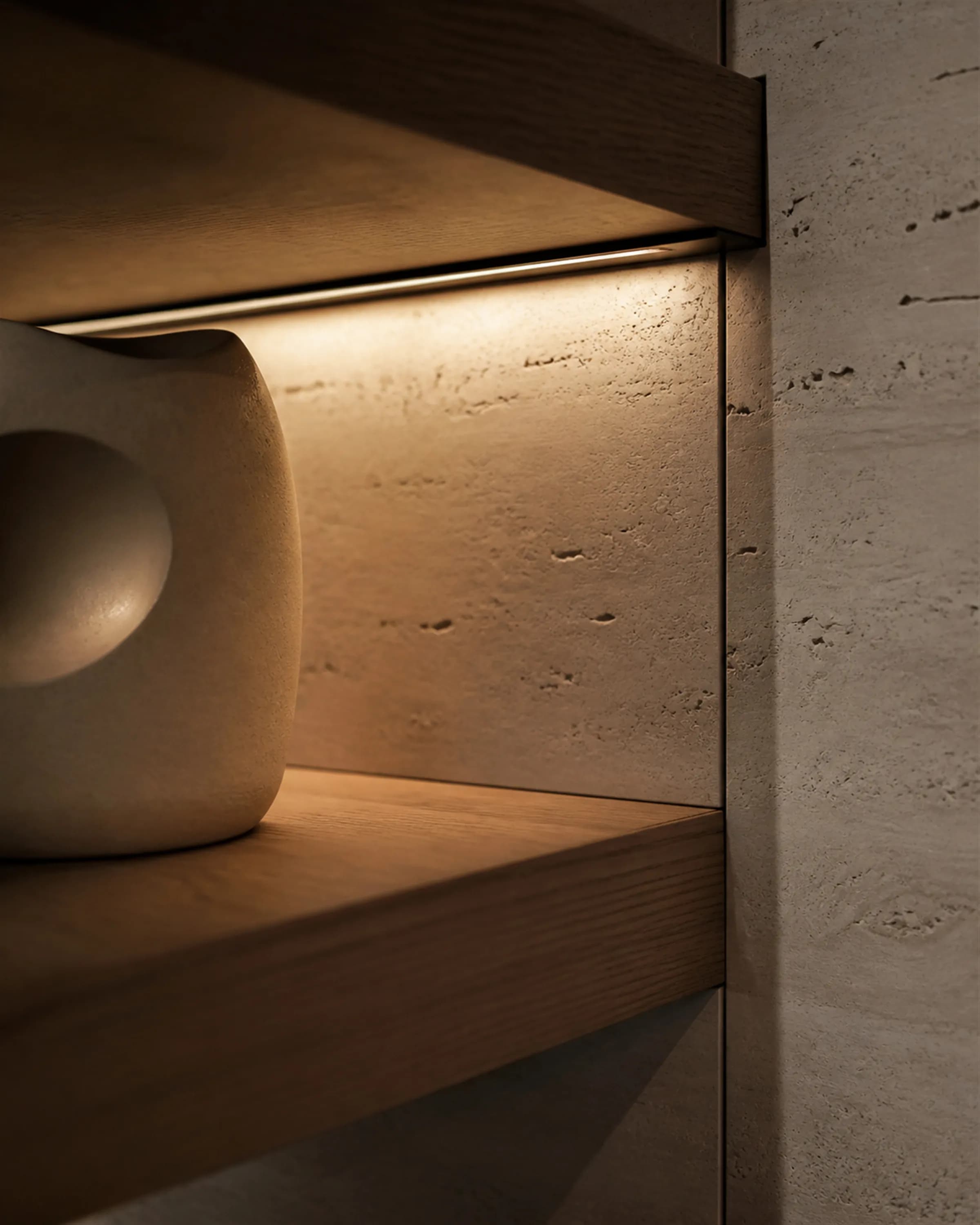 A retail display detail where a teak shelf meets travertine with a recessed bronze light channel